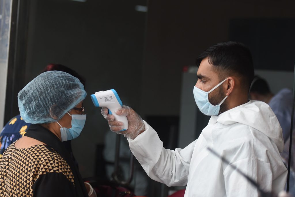 An airport official checks the temperature of a British national queueing to enter the the Hazrat Shahjalal International Airport to leave Bangladesh